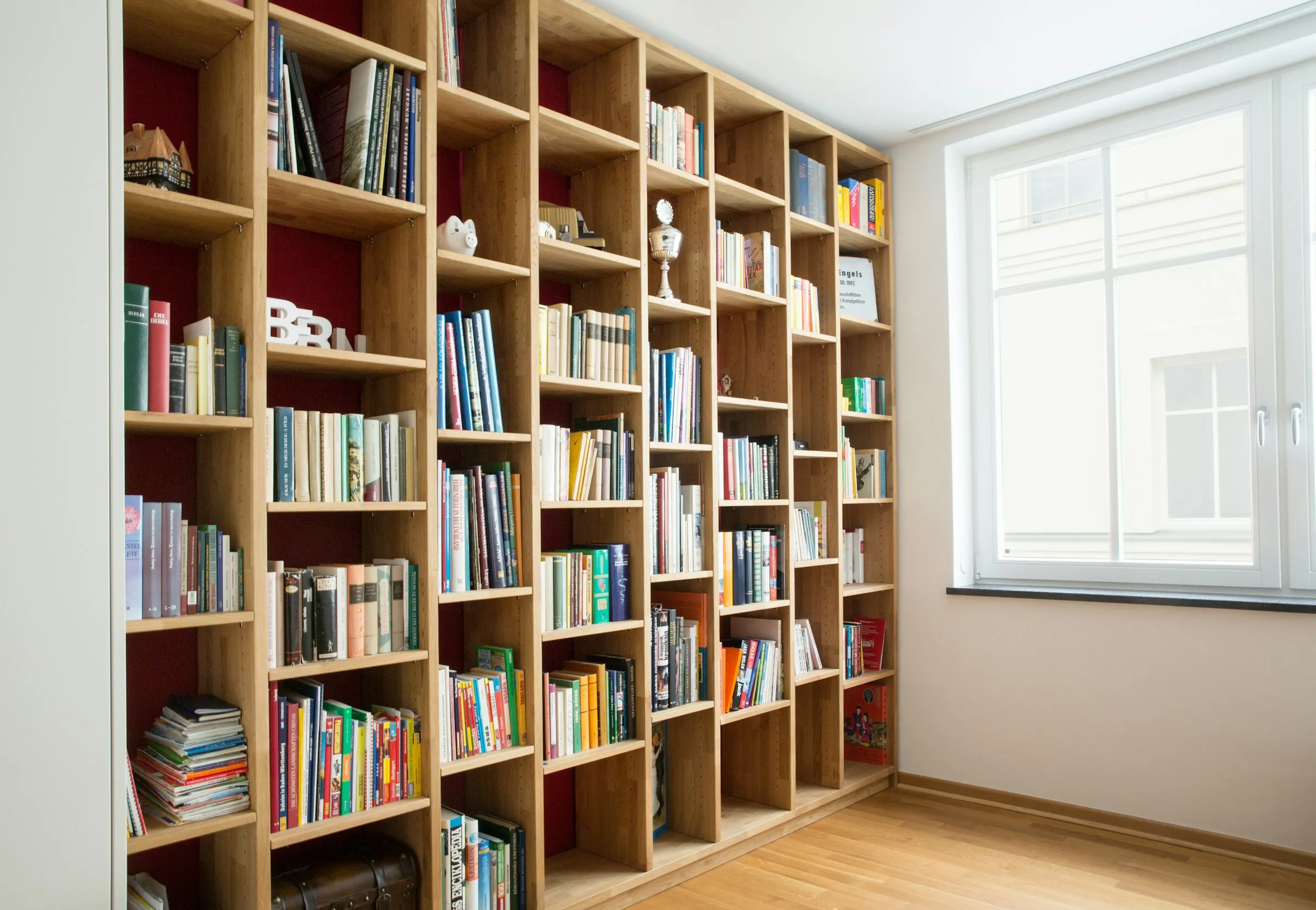 Wooden bookshelves filled with books beside a window